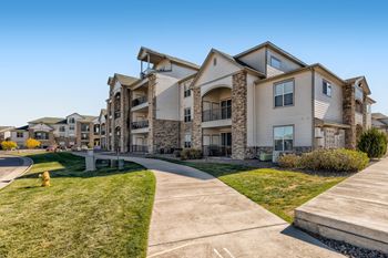 A large, modern apartment complex with a well-maintained lawn and a clear sky at Fox Run Lofts Apartments, Englewood Colorado.